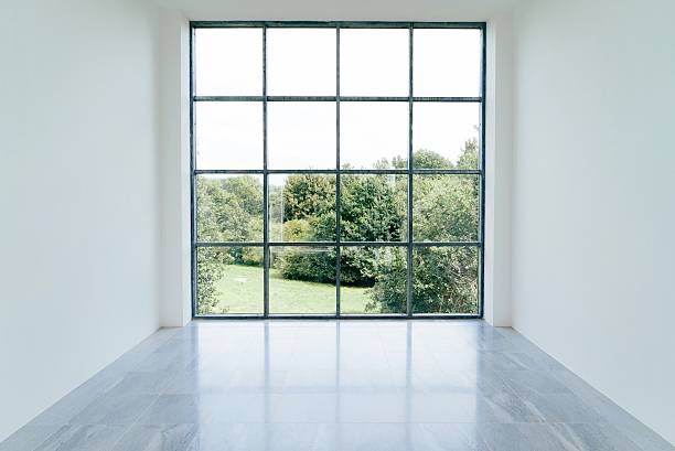 Grande pièce vide avec une immence baie vitrée donnant sur la nature